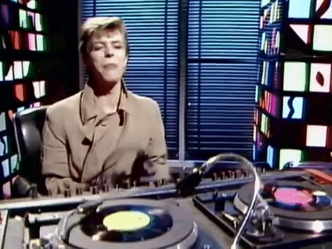 Damnit. Just reminded myself he's dead.

David Bowie puts on earphones to spin some tunes. Looks like a scene from the video for Absolute Beginners
